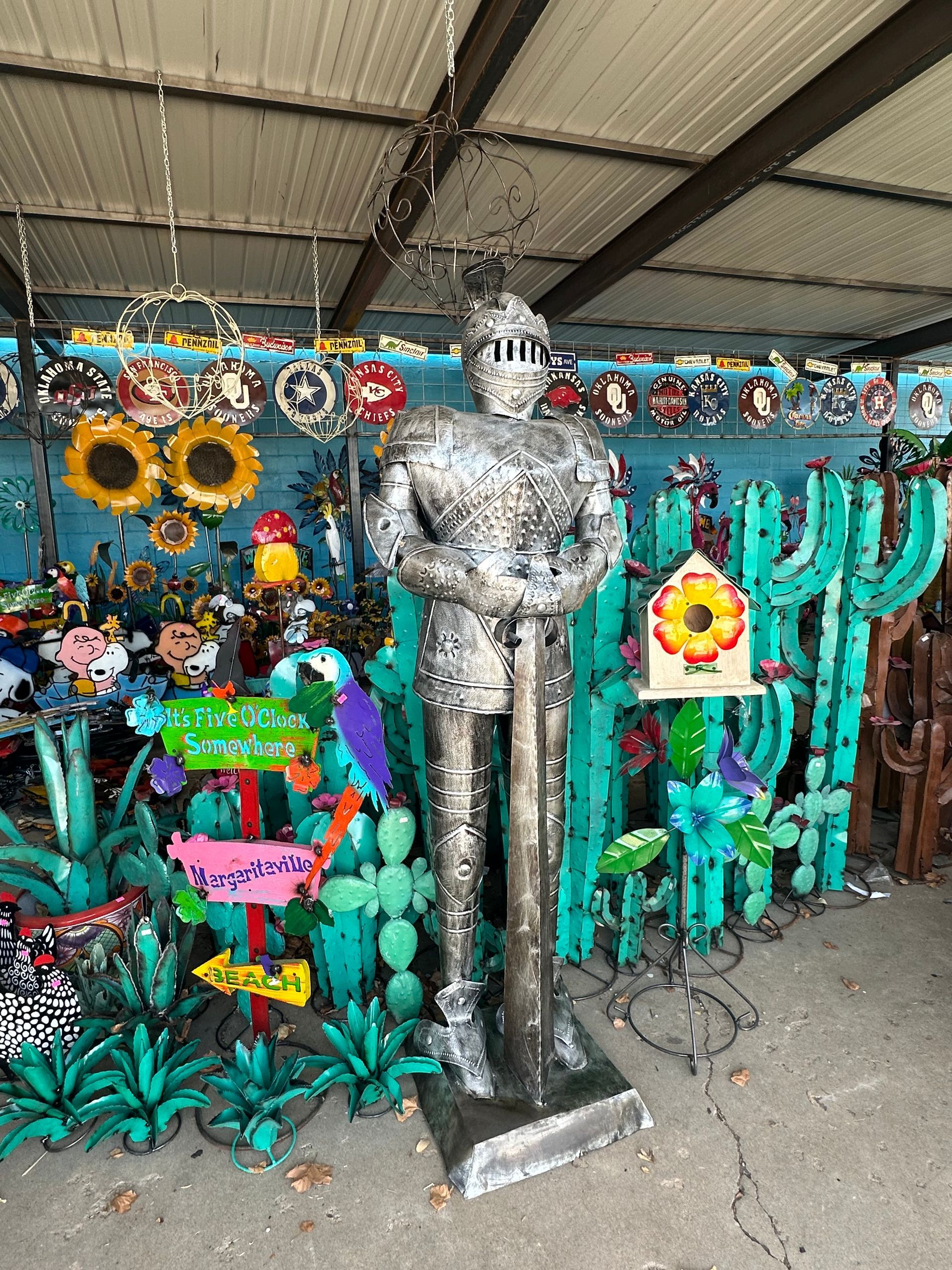 A statue of a knight in a helmet is surrounded by cactus and balloons.