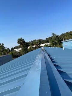 A blue roof with a gutter on it and a blue sky in the background.