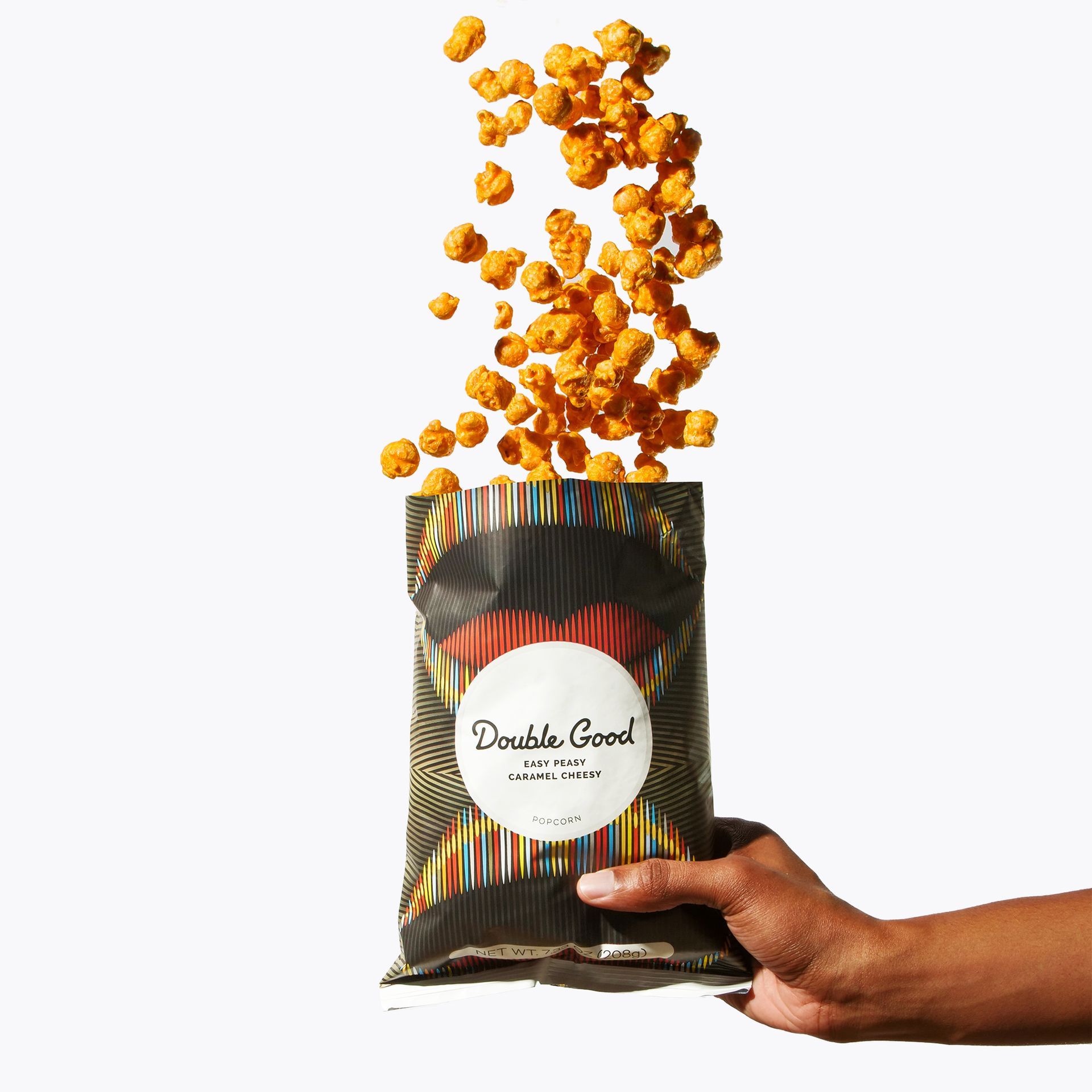 A person is holding a bag of popcorn that is being poured out of it