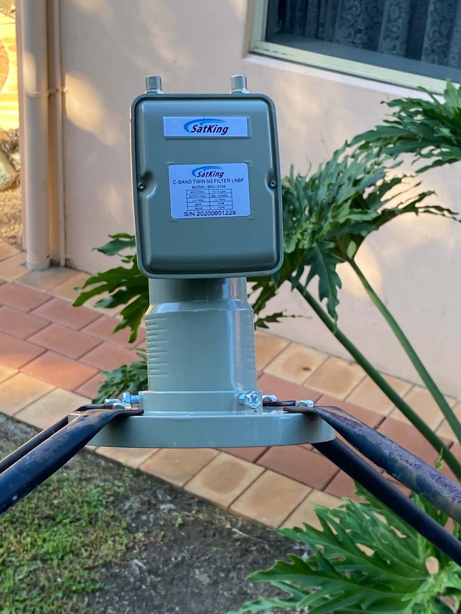A Satellite Dish is Sitting on a Brick Sidewalk Next to a Plant — Hendo's TV Antennas & Installations in White Rock, QLD