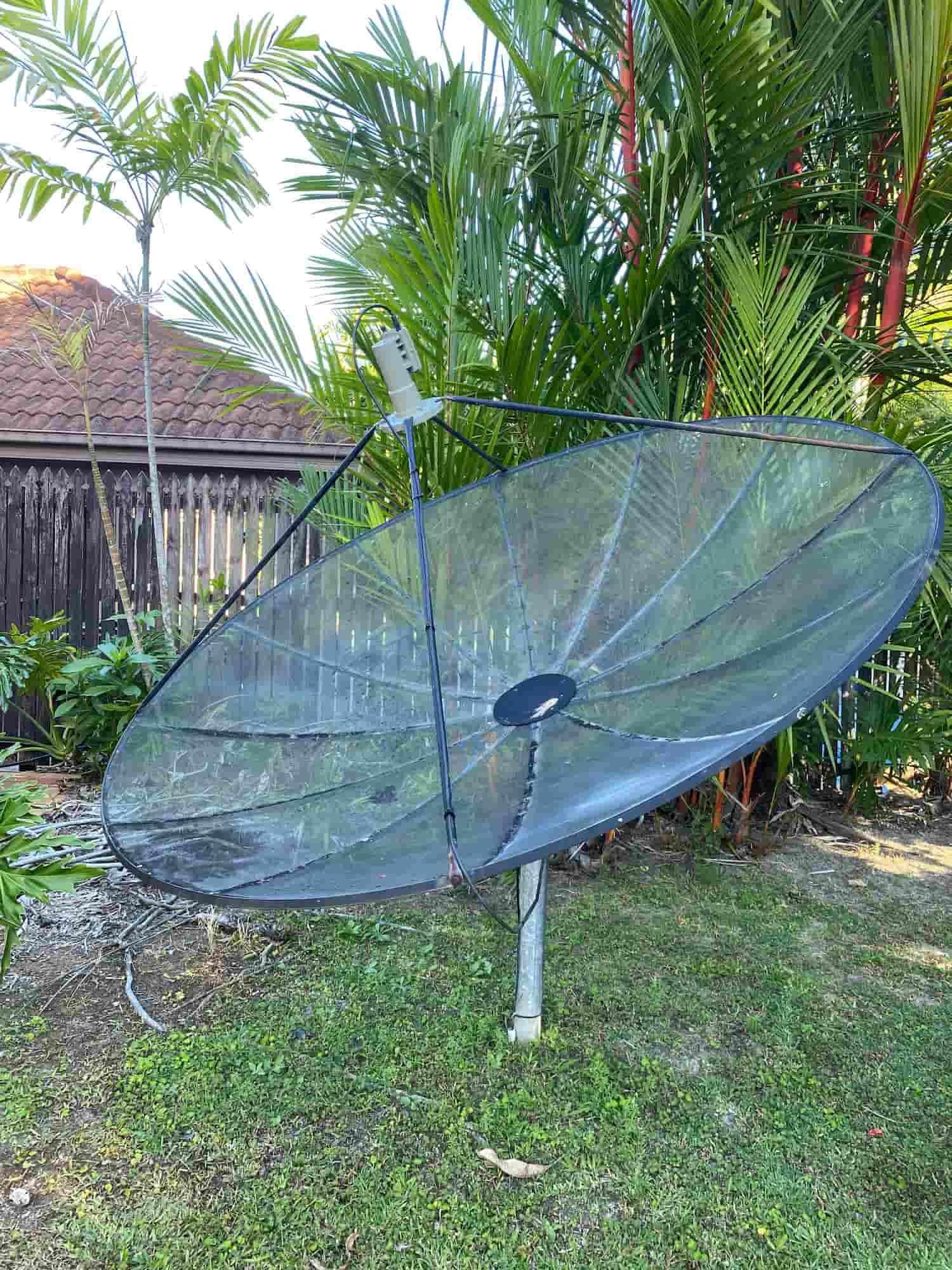 A Large Satellite Dish is Sitting on Top of a Lush Green Field — Hendo's TV Antennas & Installations in White Rock, QLD