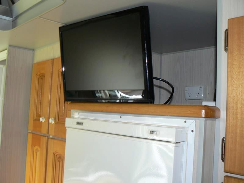 A Flat Screen Tv is Mounted Above a White Refrigerator — Hendo's TV Antennas & Installations in White Rock, QLD