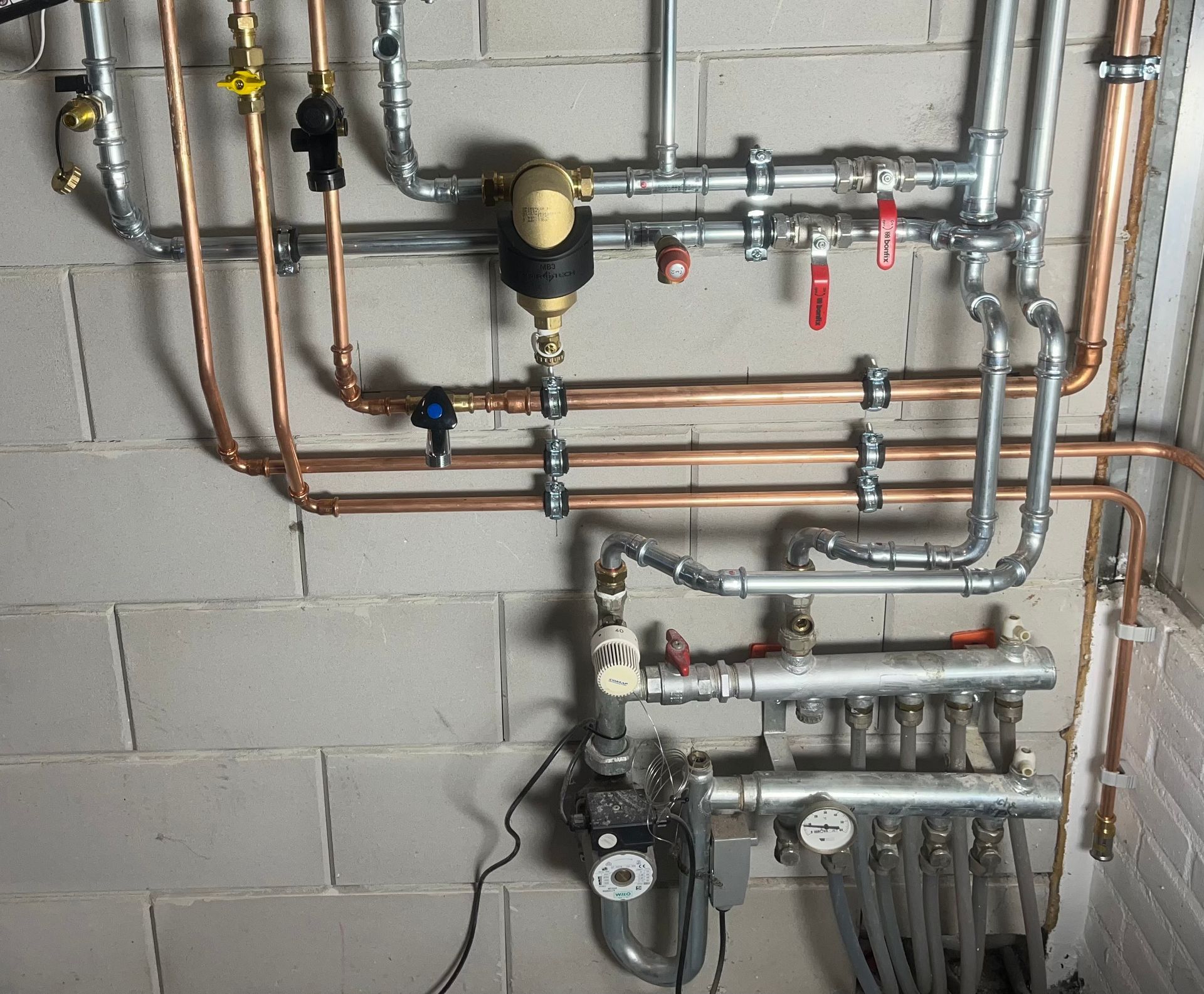 Een stel pijpen hangt aan een bakstenen muur