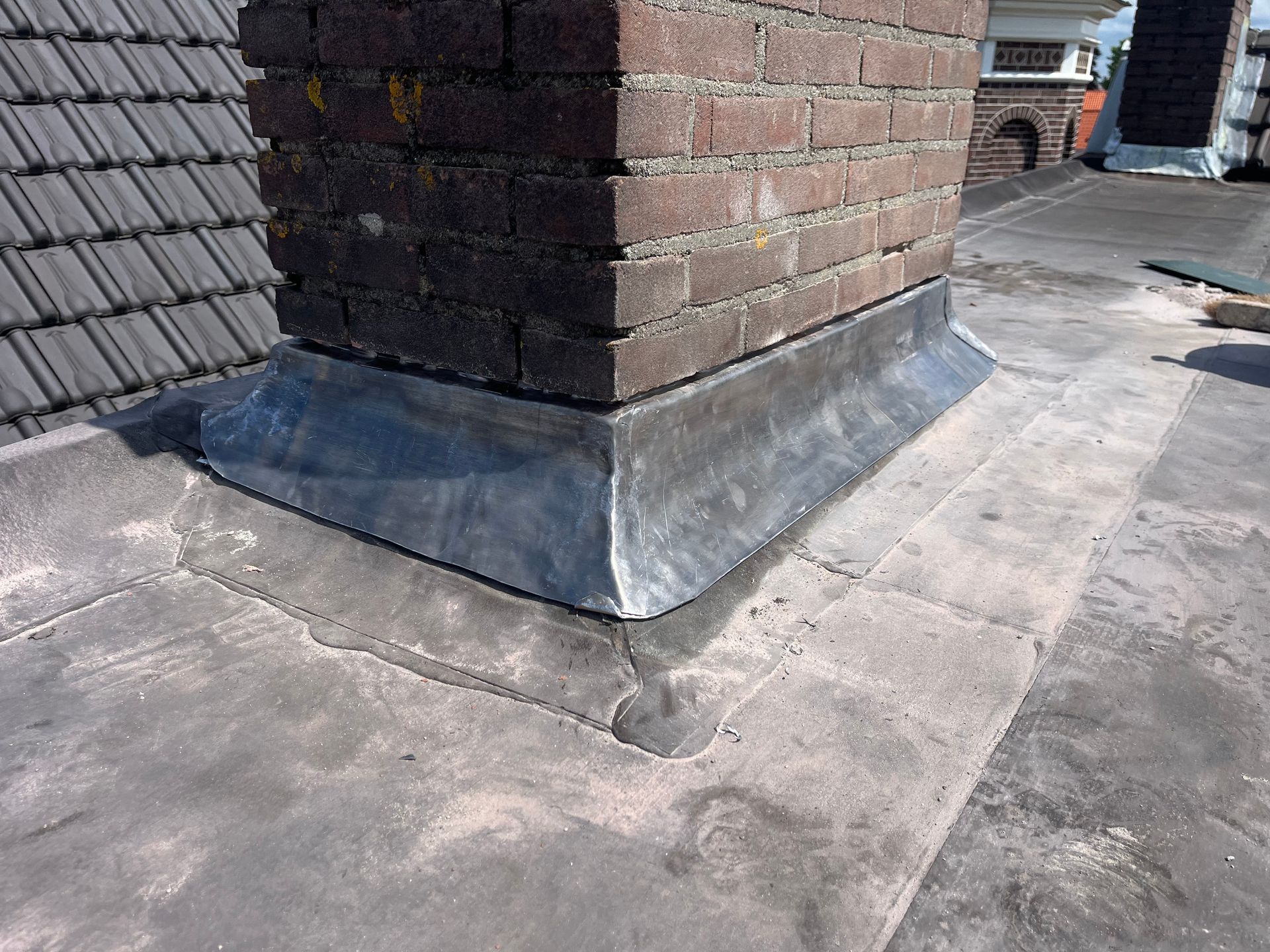 Een bakstenen schoorsteen staat op een dak