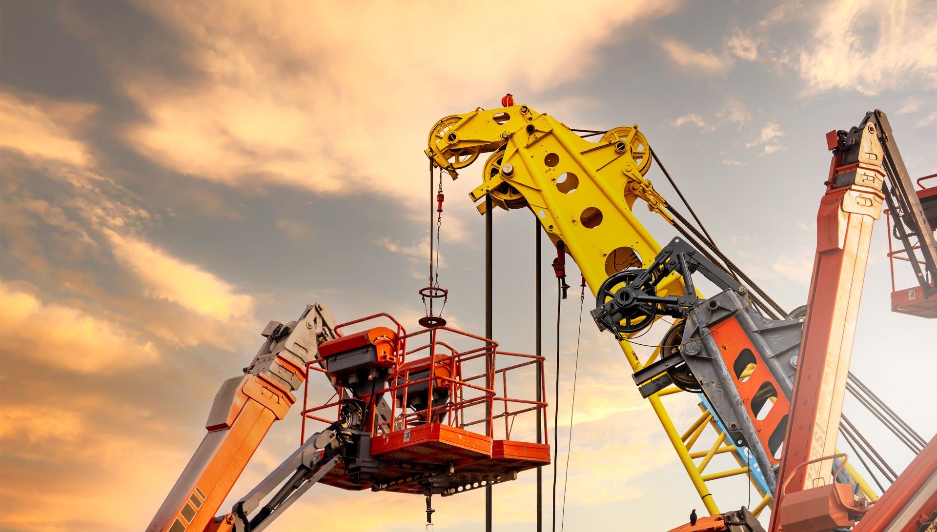 Articulated boom lift. Aerial platform lift and construction crane with sunset sky. 