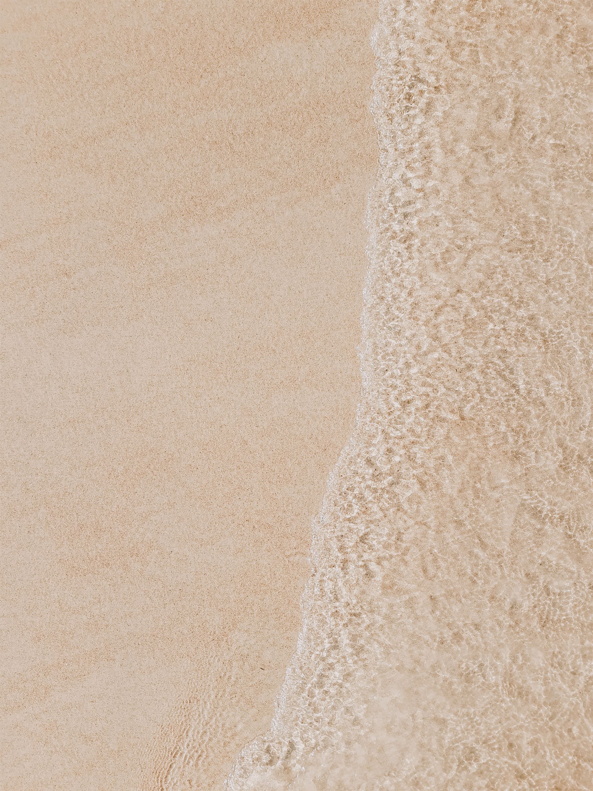 Un primer plano de una ola en una playa de arena.