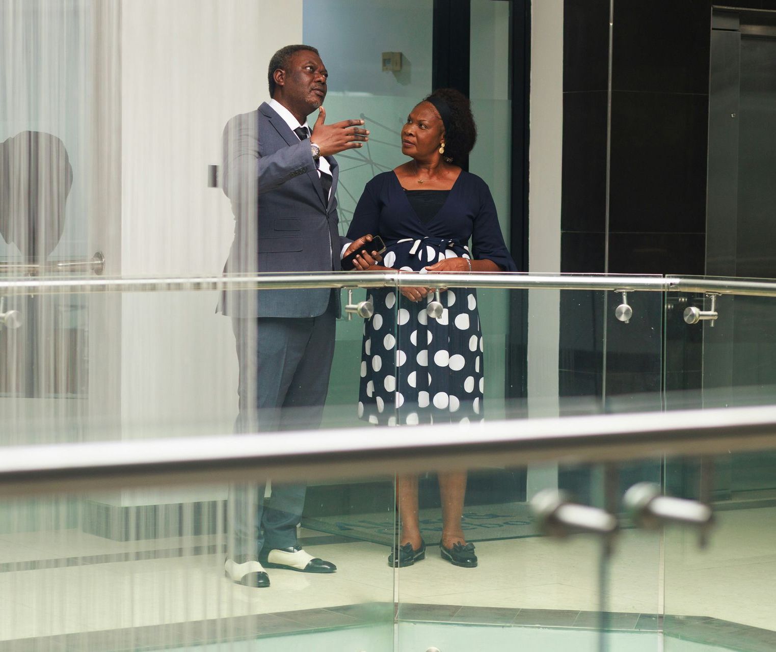 A man and a woman are standing on a balcony talking to each other.