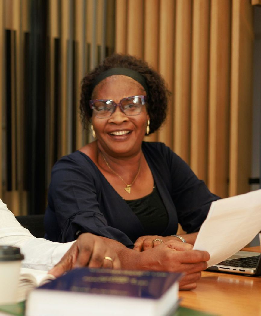A woman wearing glasses is smiling while sitting at a table