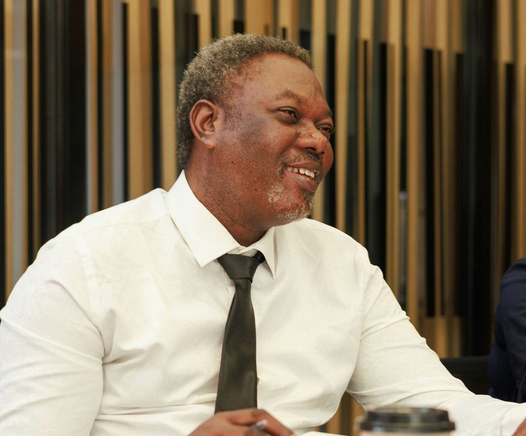 A man in a white shirt and tie is smiling