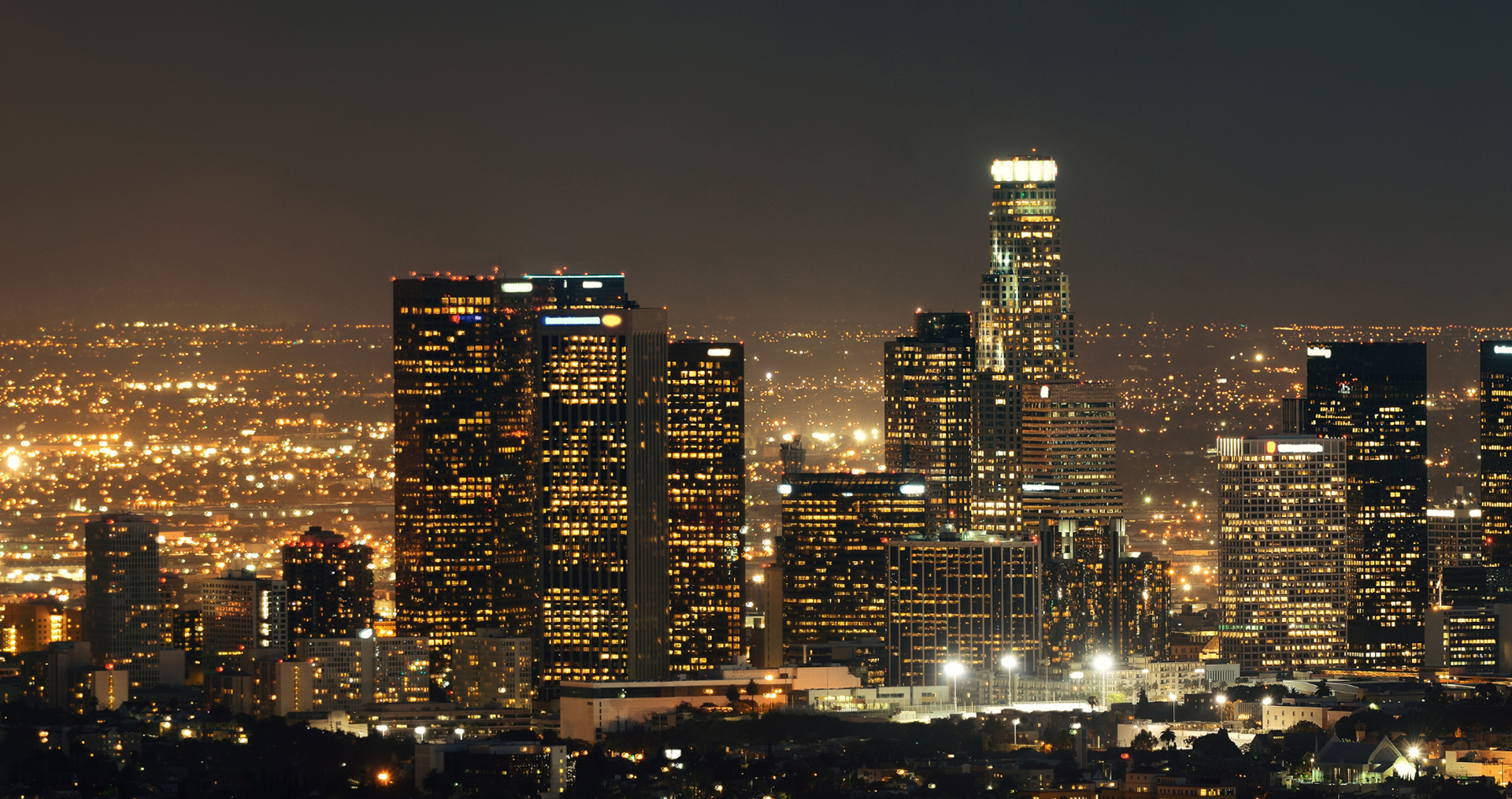 An aerial view of a city at night with a tall building in the foreground.