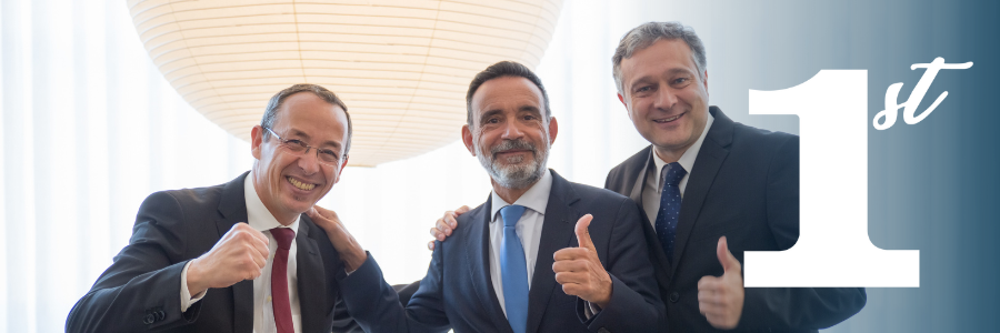 Three men in suits smiling, giving thumbs up, and celebrating;