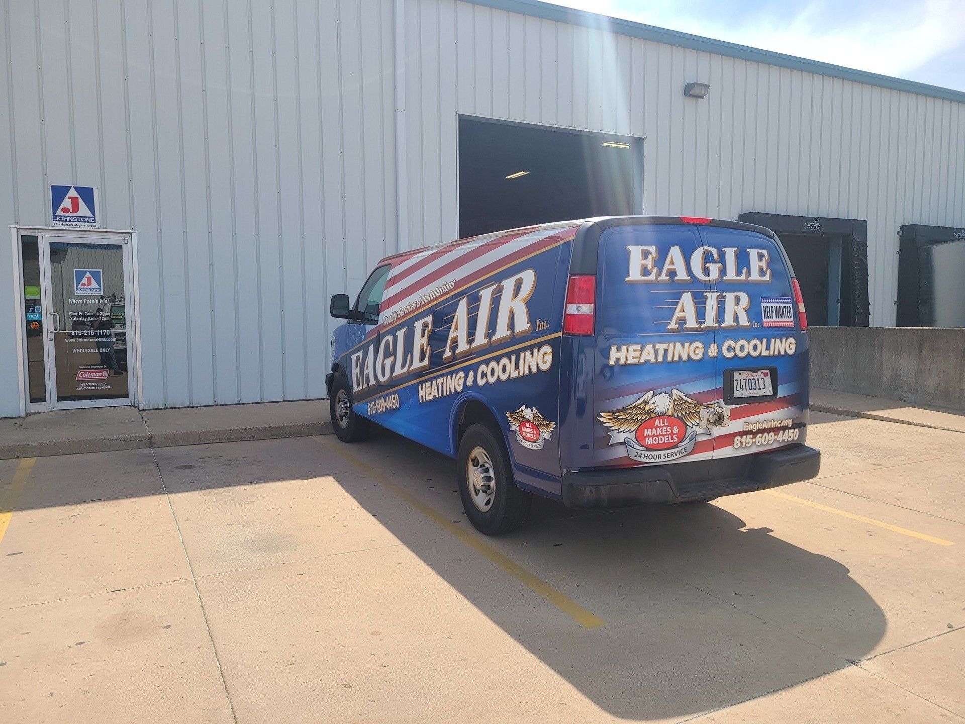 Blue Eagle Air van parked in front of a building with a glass door.