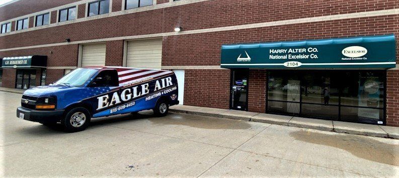 A van with a US flag design in front of a brick building with a green awning. Eagle Air sign is on the van.