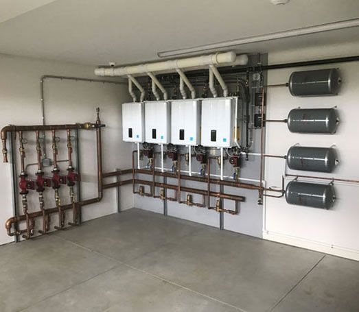 Heating system with boilers, pipes, and expansion tanks in an industrial room.