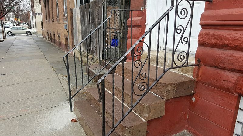 A set of stairs with a wrought iron railing on the side of a building.
