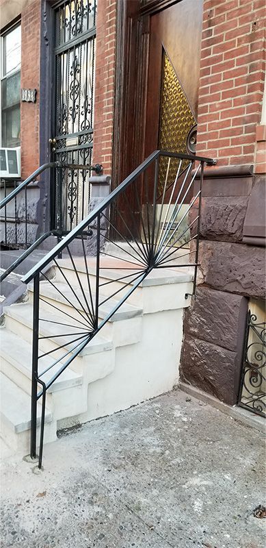 A set of stairs leading up to a brick building with a wrought iron railing.