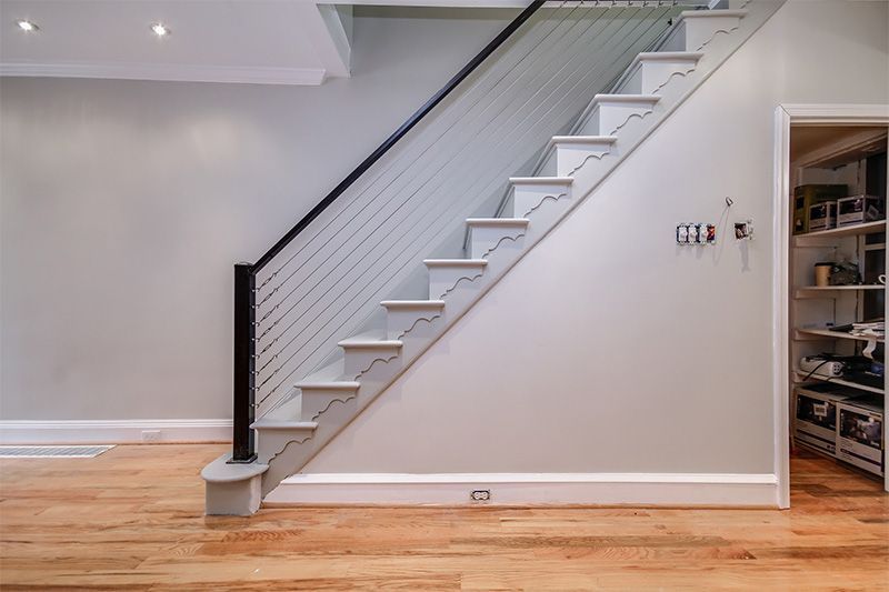 A staircase with a black railing is in a room with hardwood floors.