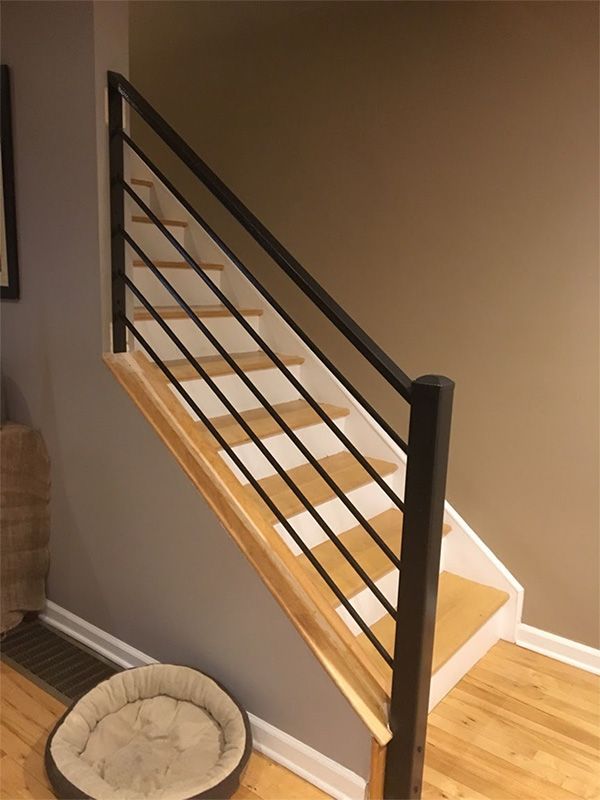 A dog bed sits next to a staircase with a black railing