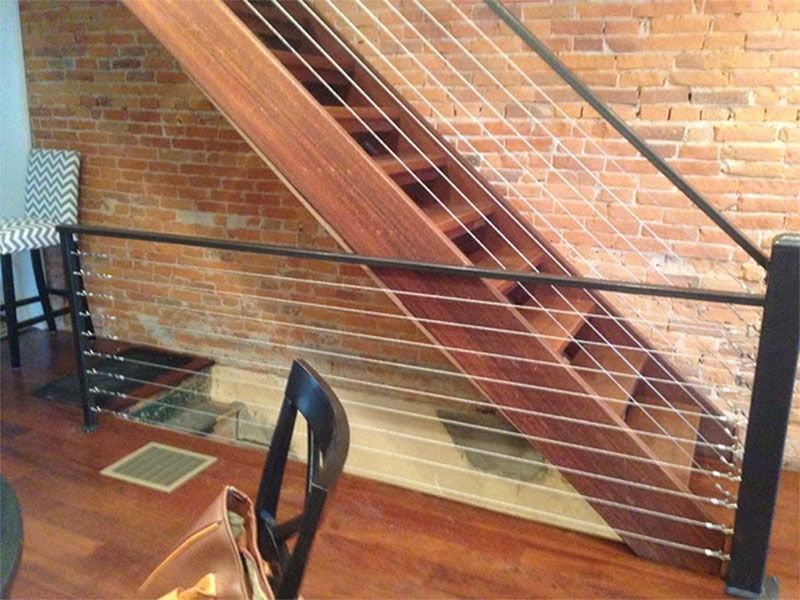 A wooden staircase with a metal railing in front of a brick wall