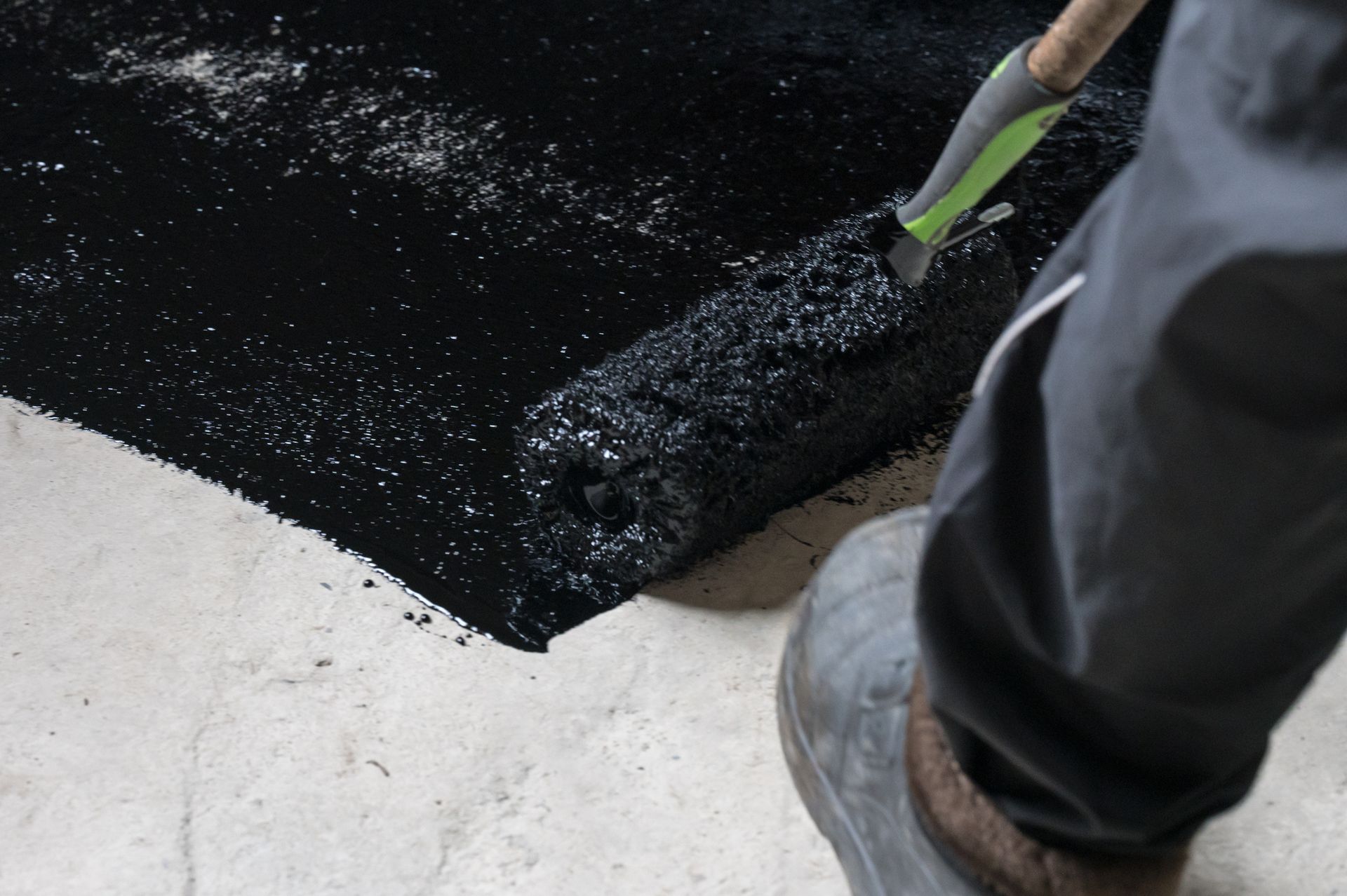 Close-up of a commercial waterproofing contractor applying liquid resin to the concrete floor. Close-up of a commercial waterproofing contractor applying liquid resin to the concrete floor.