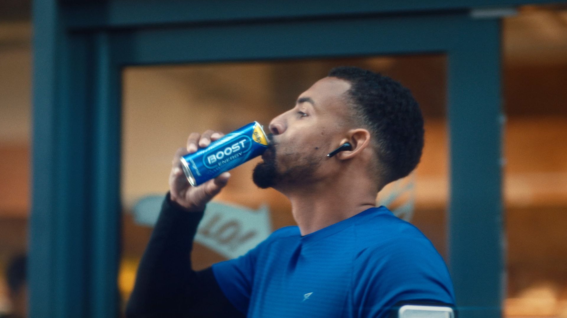 A man is drinking a can of boost energy drink.
