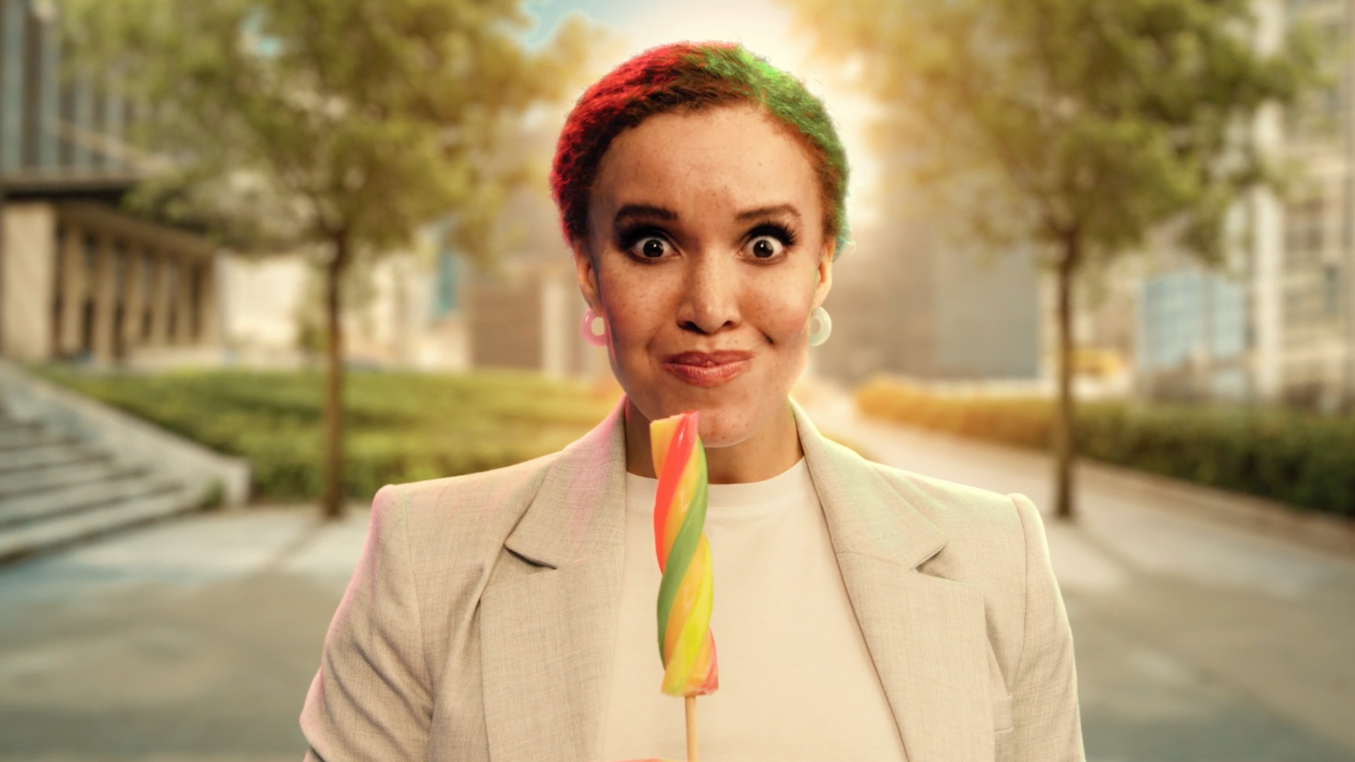 A woman is holding a colorful lollipop in her mouth.