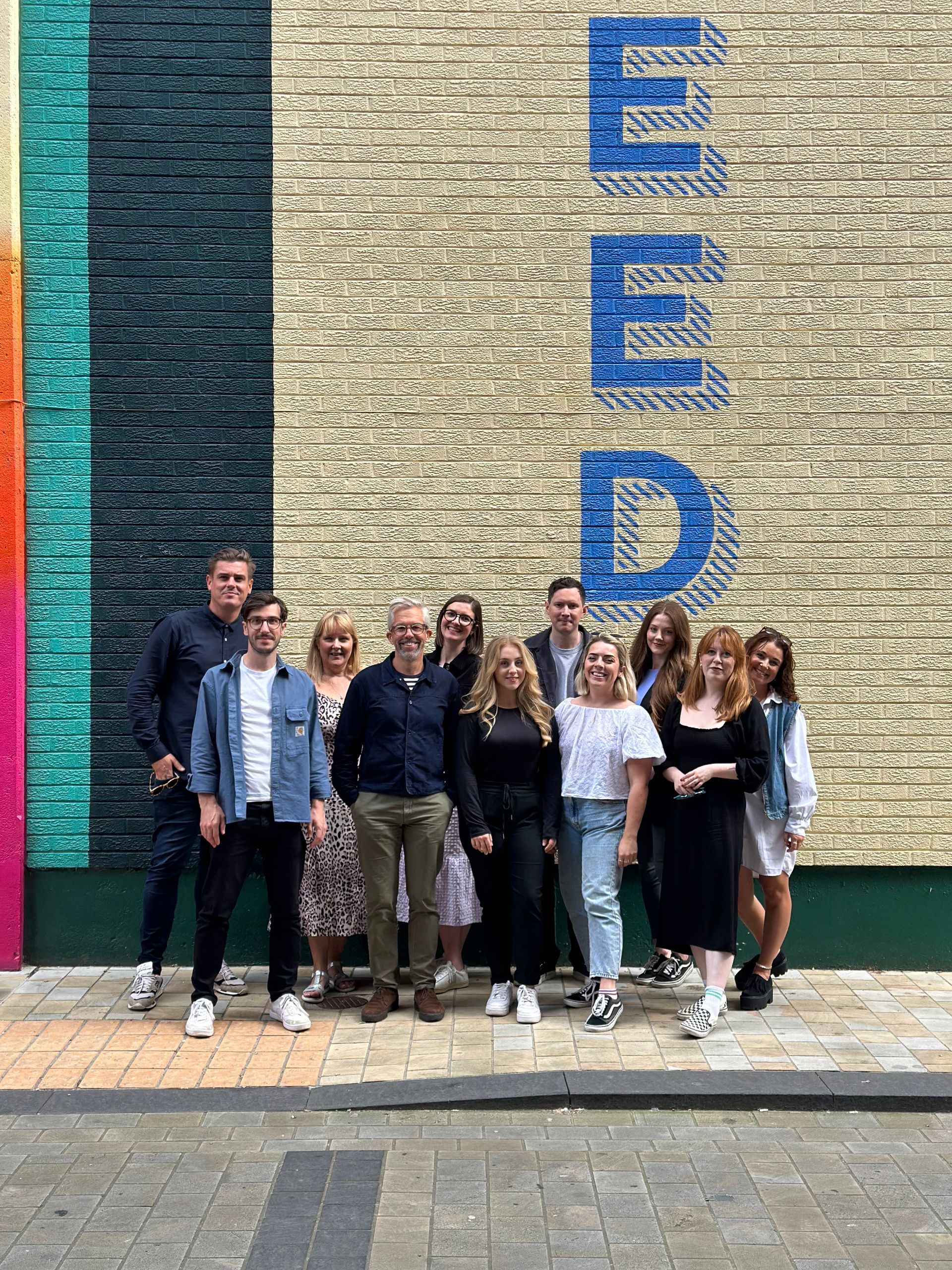 A group of people are posing for a picture in front of a brick wall.