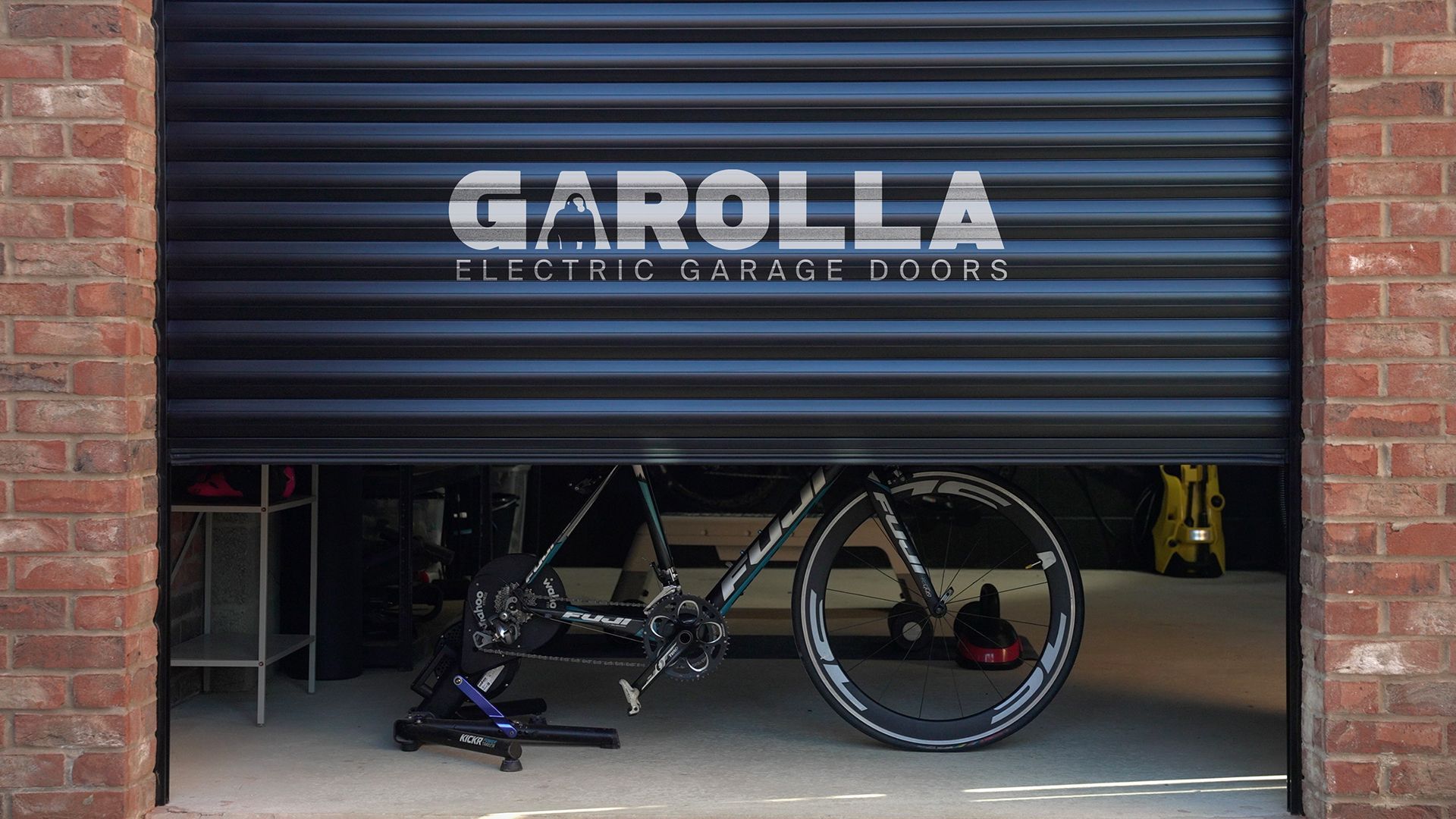 A bicycle is parked in a garage with a black garage door.