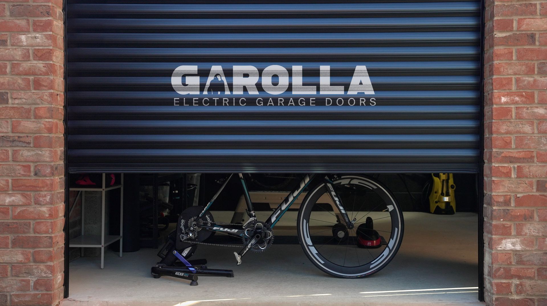 A bicycle is parked in a garage with a black garage door.