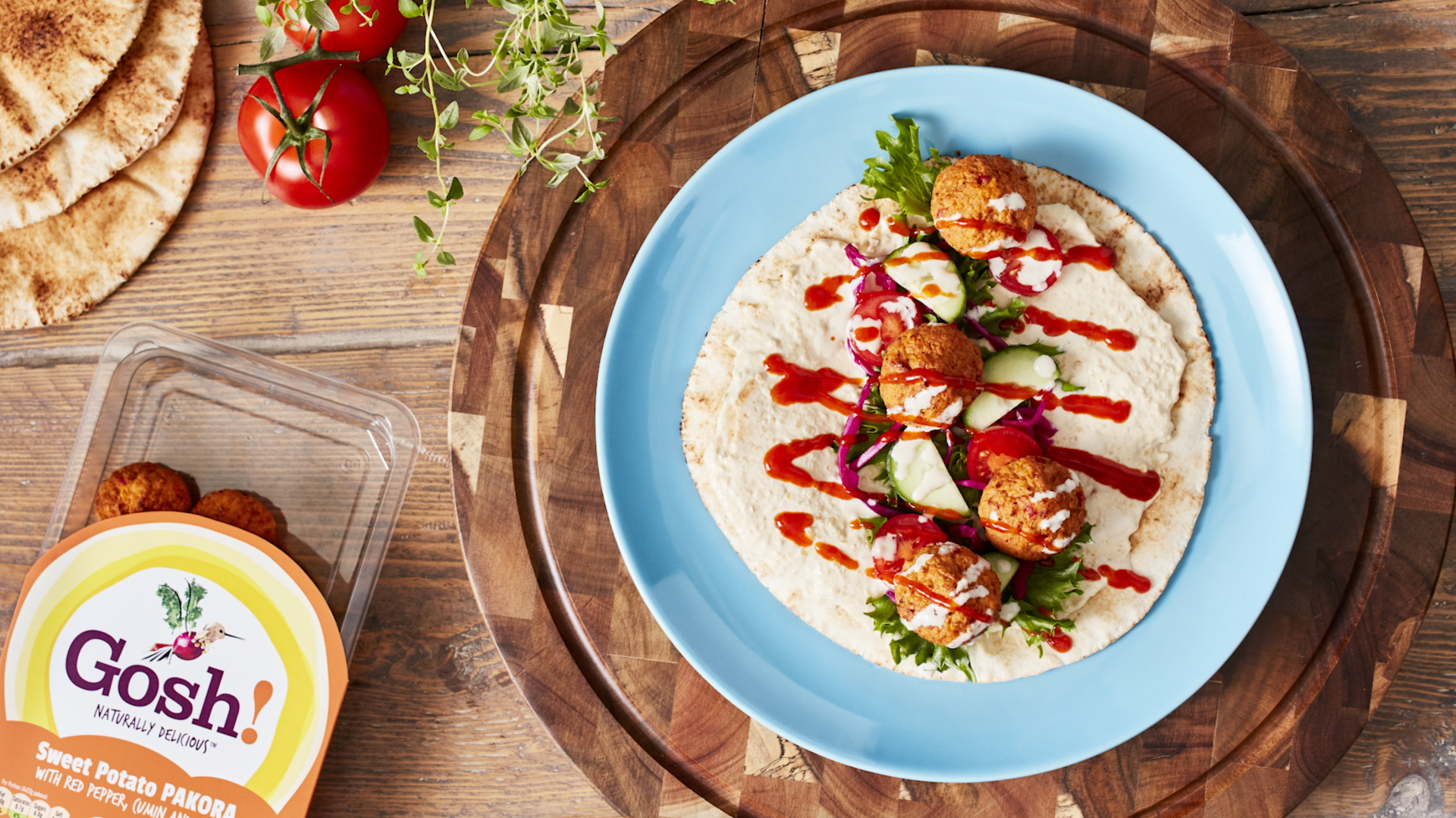 A blue plate topped with a tortilla filled with meatballs and vegetables.