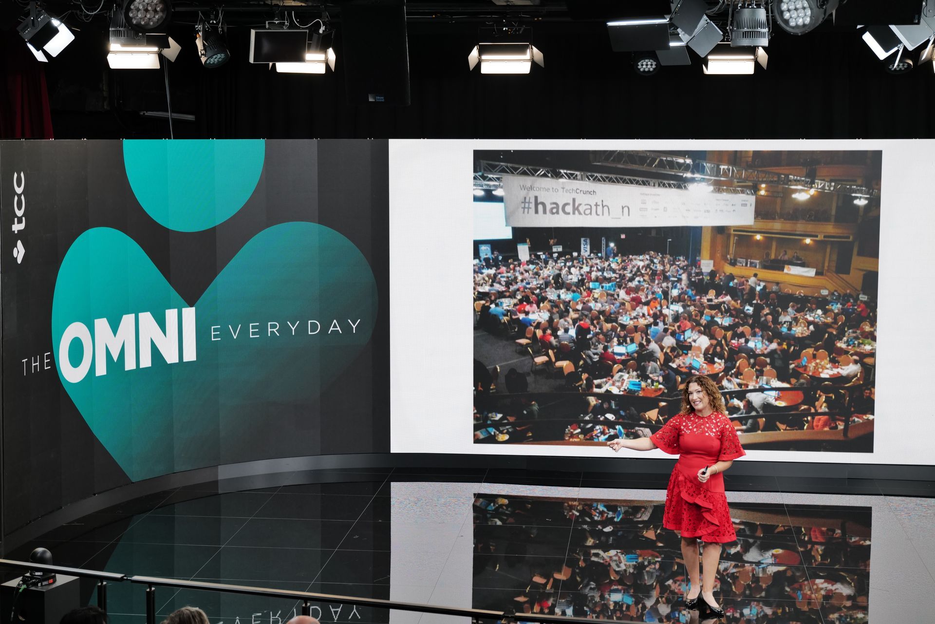 A woman in a red dress is standing in front of a screen that says the omni everyday