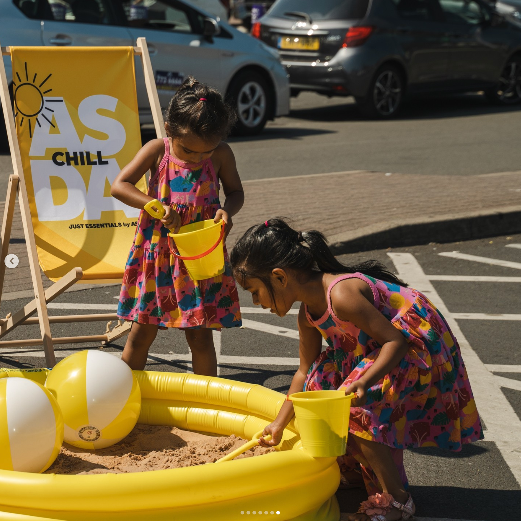 Two little girls are playing in a sandbox with a sign that says chill on it