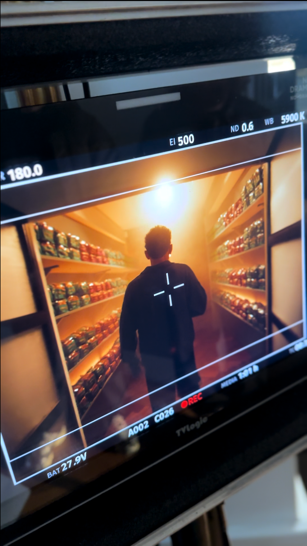 Monitor showing a person walking toward bright light between shelves of items.