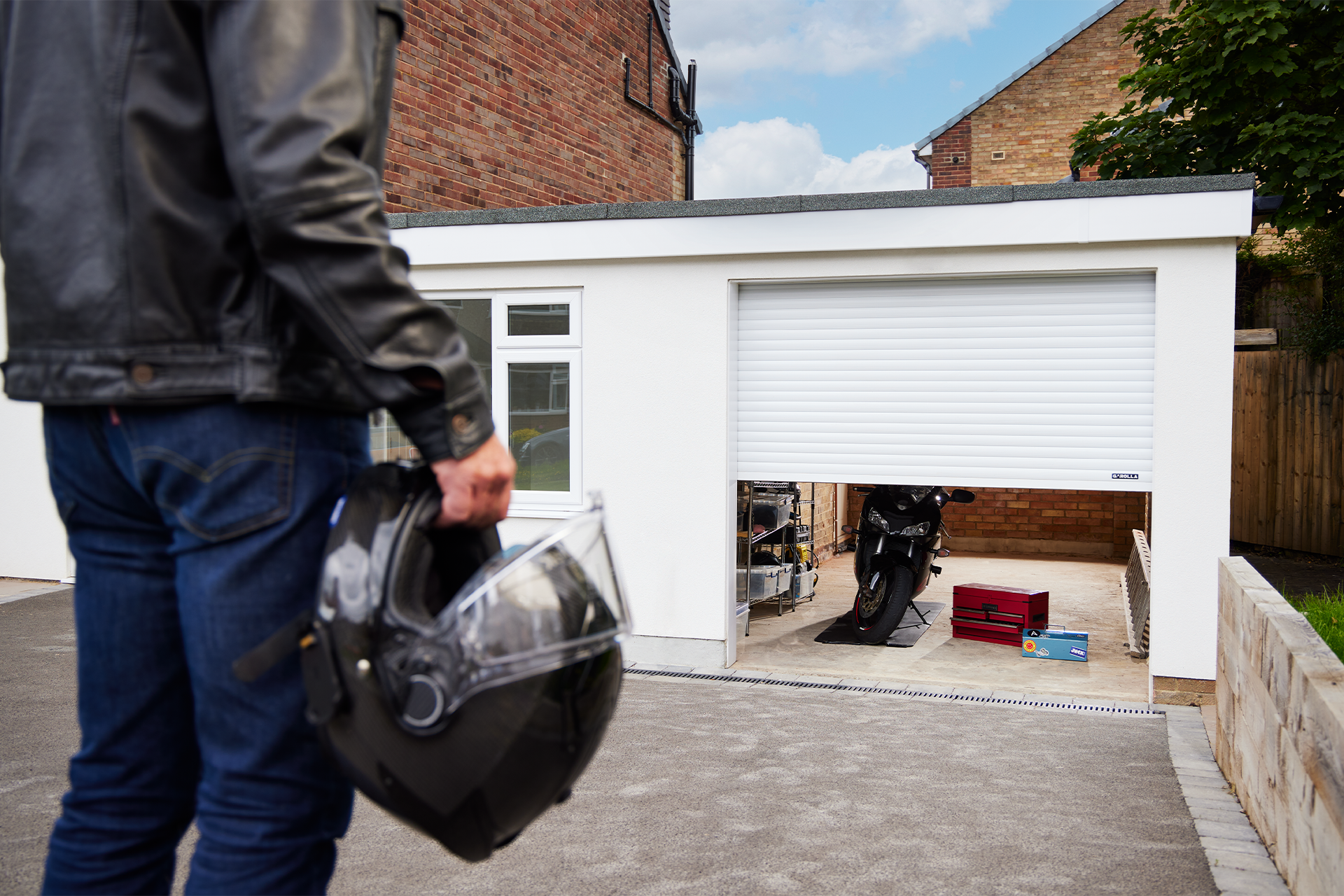 A man is holding a helmet in front of a garage door.