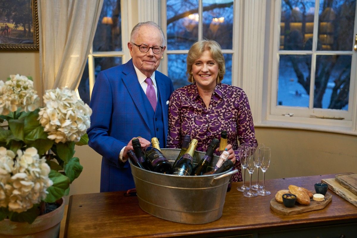 A man and a woman are standing next to each other holding a bucket of wine.