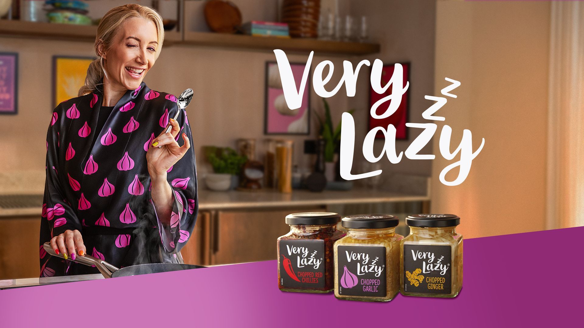 Woman in kitchen, holding utensil, with jars of 