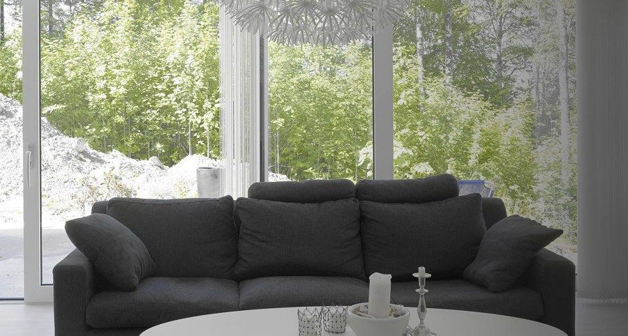 Dark gray sofa in a modern living room with large windows overlooking trees.
