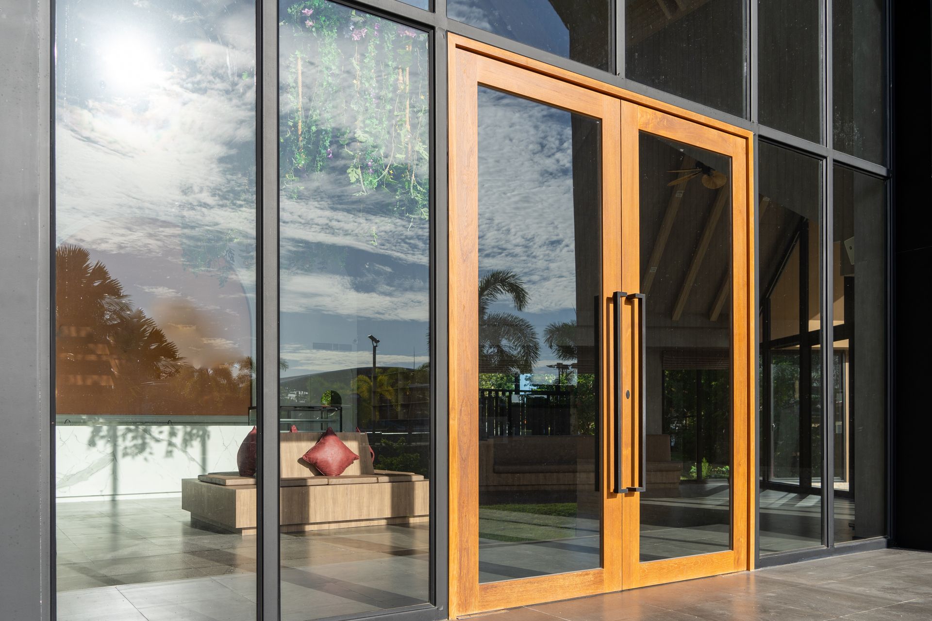 Double wooden-framed glass doors set within a large, modern glass storefront, showing a lobby with furniture inside.