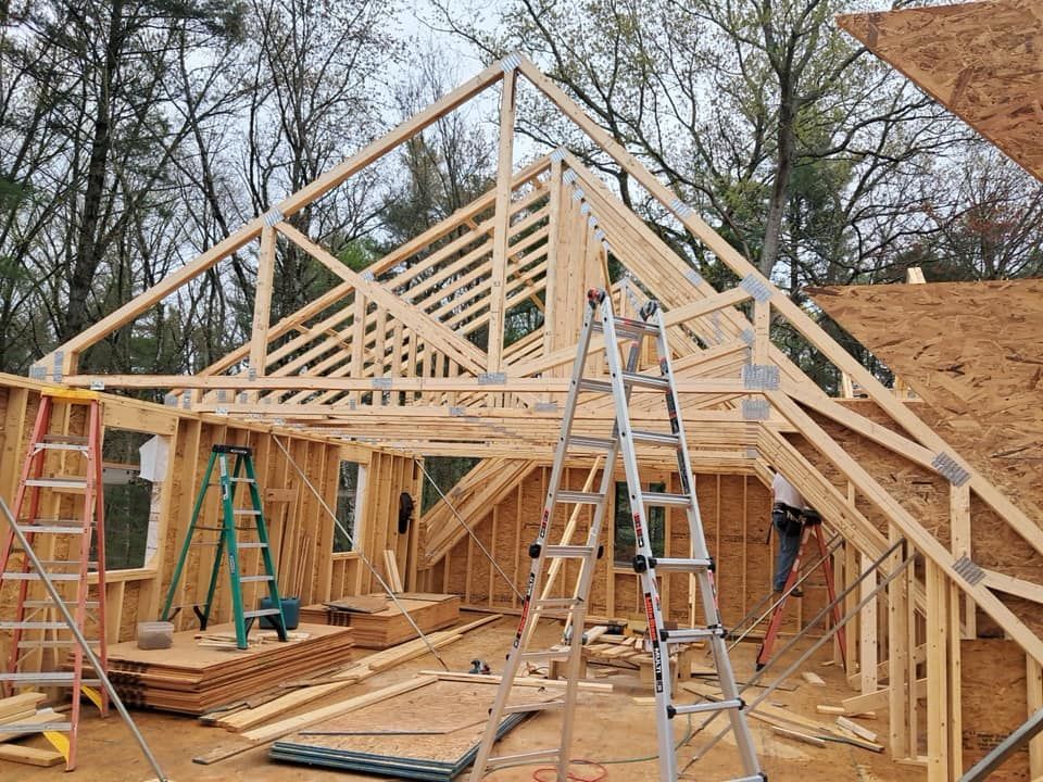 Woman in straw hat smiles, holding wine glass near a lake.