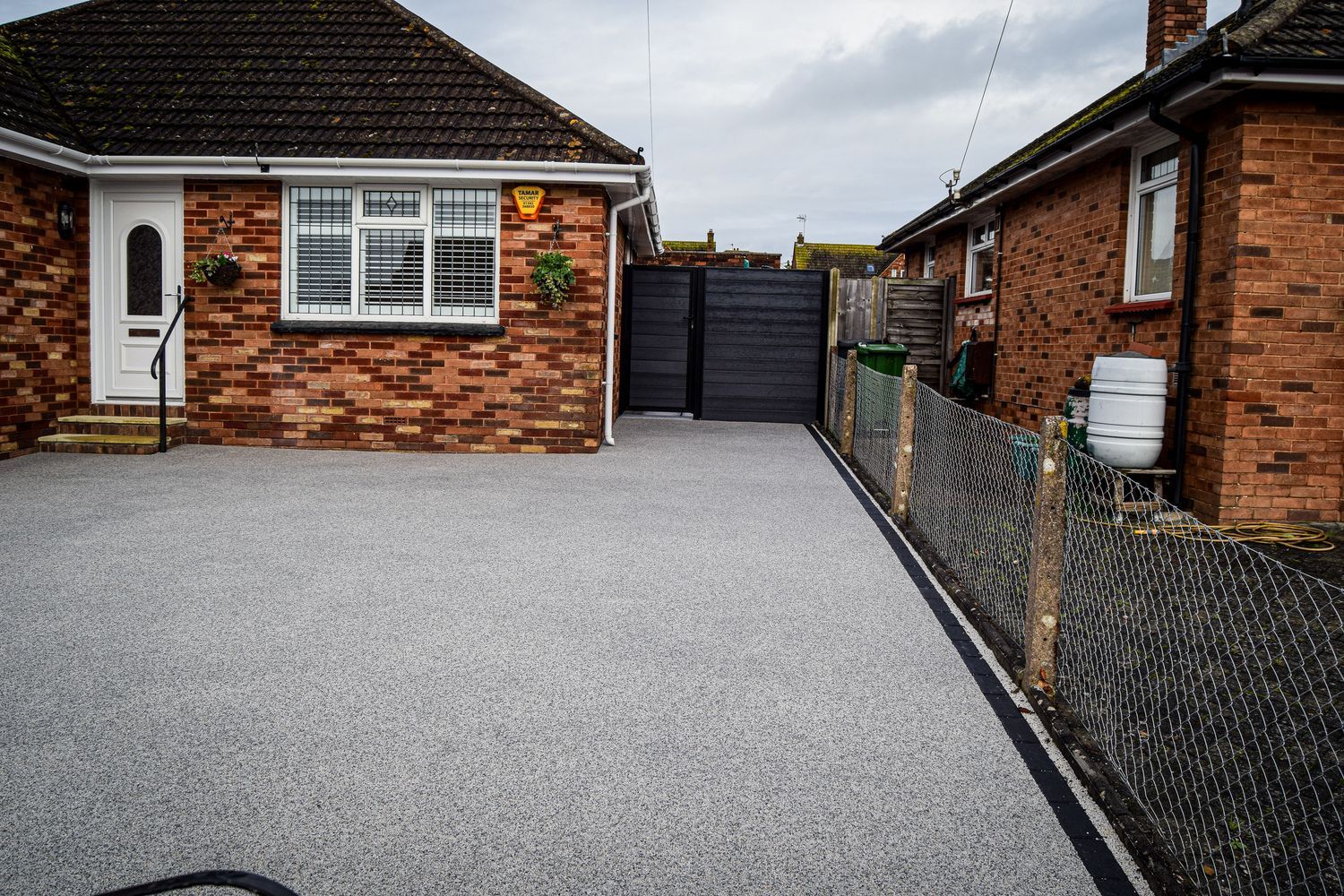 Grey resin driveway outside a red brick bungalow