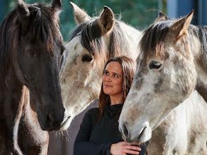 A woman is standing next to three horses.