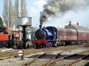 A blue and red train is going down train tracks.