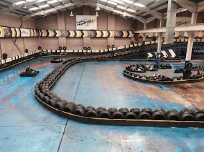 A group of people are riding go karts on a track in a building.