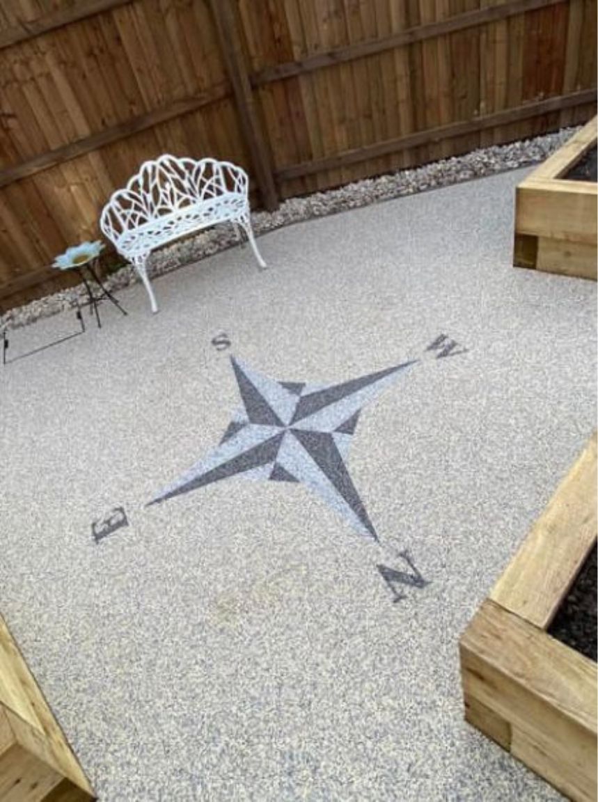 Grey resin driveway with a light and dark grey compass pattern on it