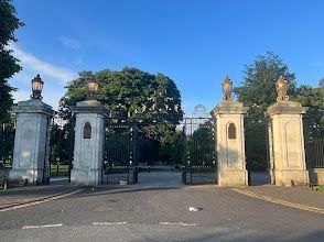 A row of columns leading to a gate in a park.