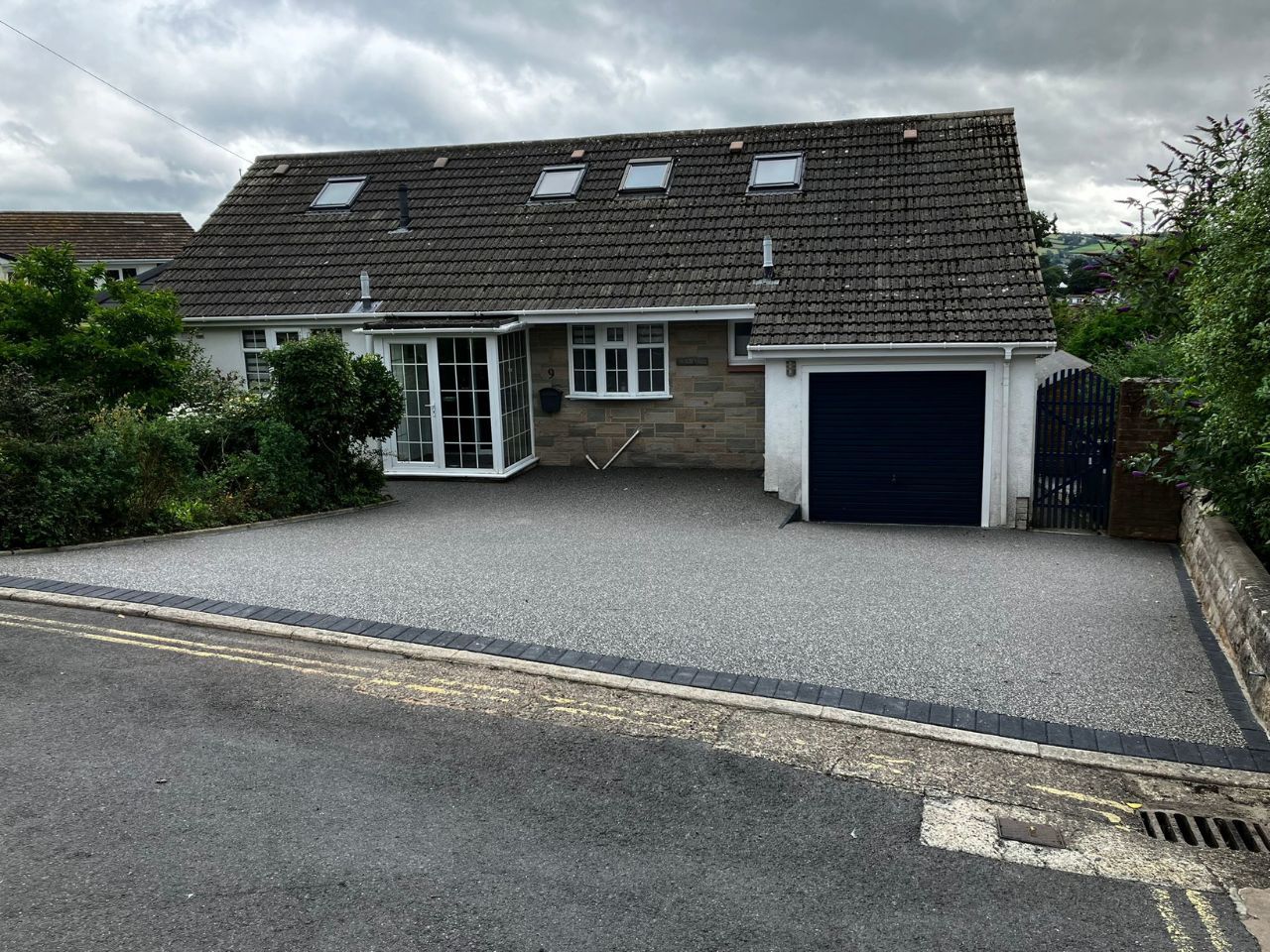 Grey resin driveway with a block paving border, outside a bungalow