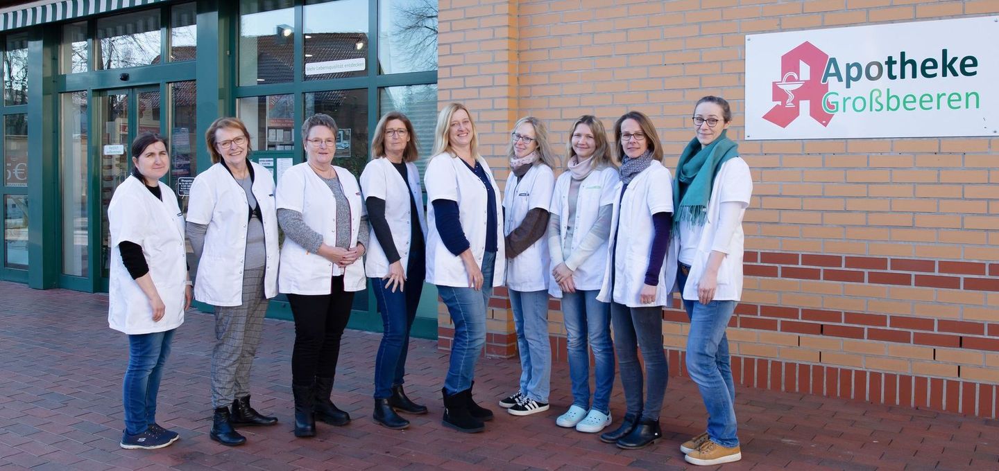 Eine Gruppe von Frauen posiert vor einer Apotheke für ein Foto.