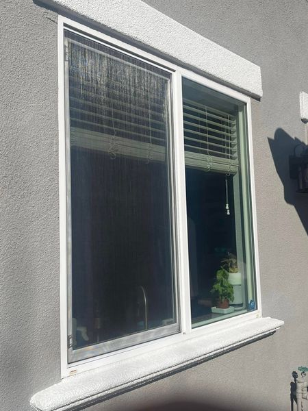 A window with blinds on it is on the side of a building.