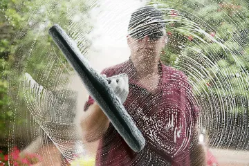 A man is cleaning a window with a squeegee.