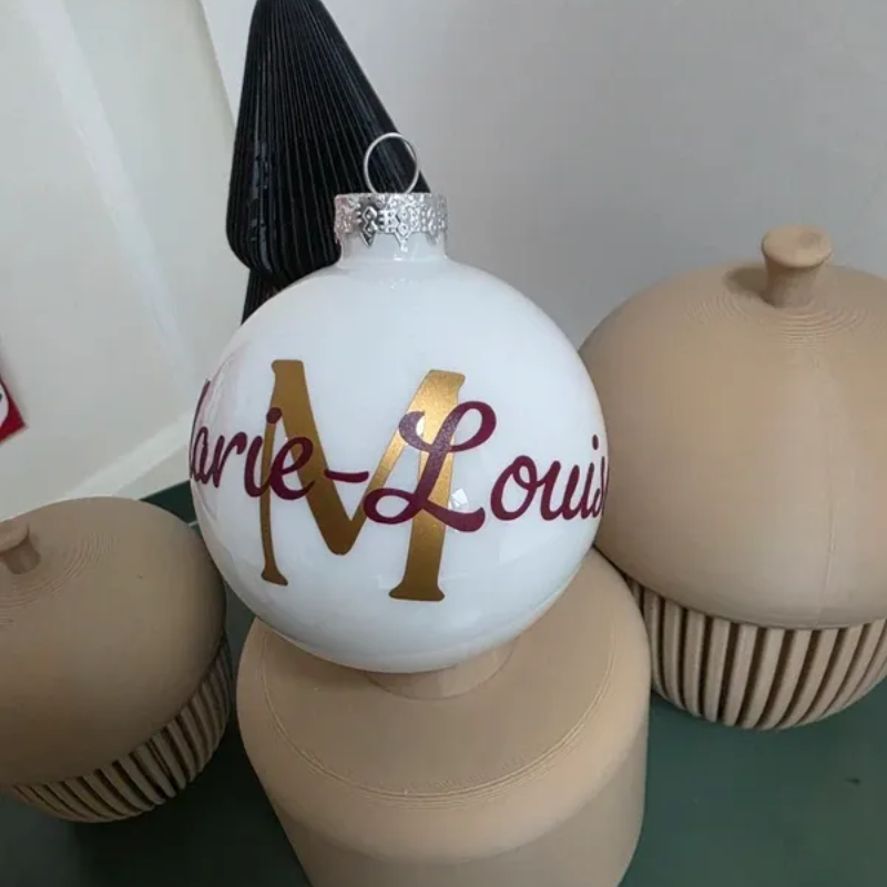 Witte kerstversiering met een gouden A en bordeauxrode tekst 